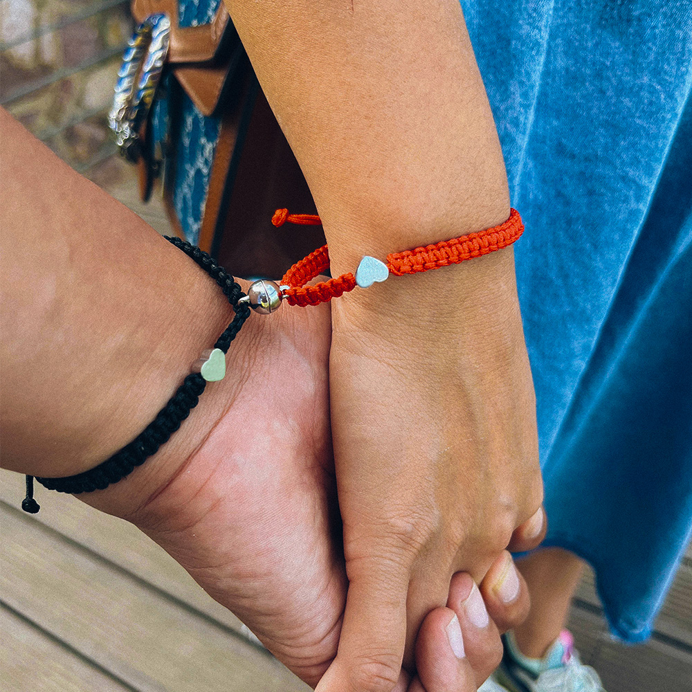 deux mains qui portes des bracelets pour couple avec des initiales 