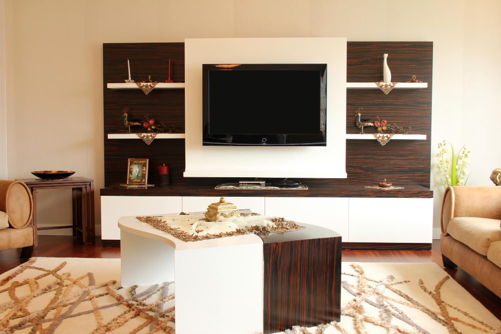 Un salon moderne avec un petit meuble TV bicolore, blanc et bois foncé, entouré d'étagères assorties.
